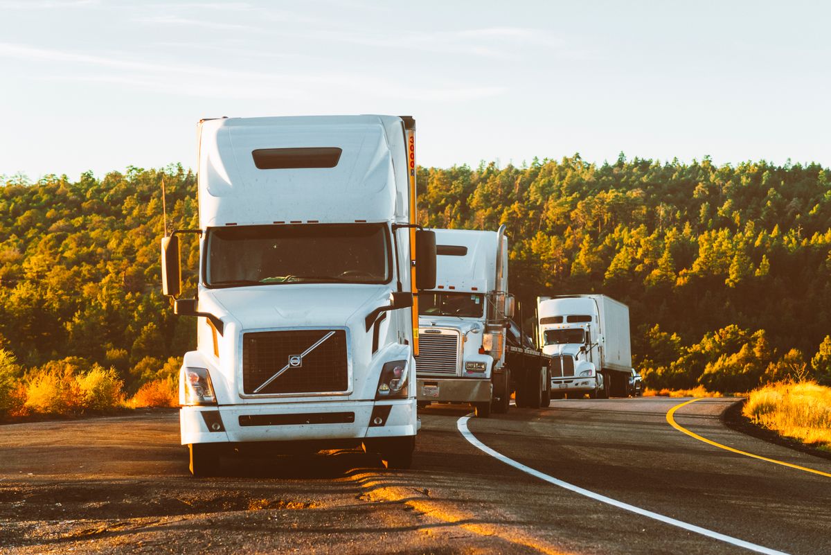 Semi trucks running a tree-lined regional highway
